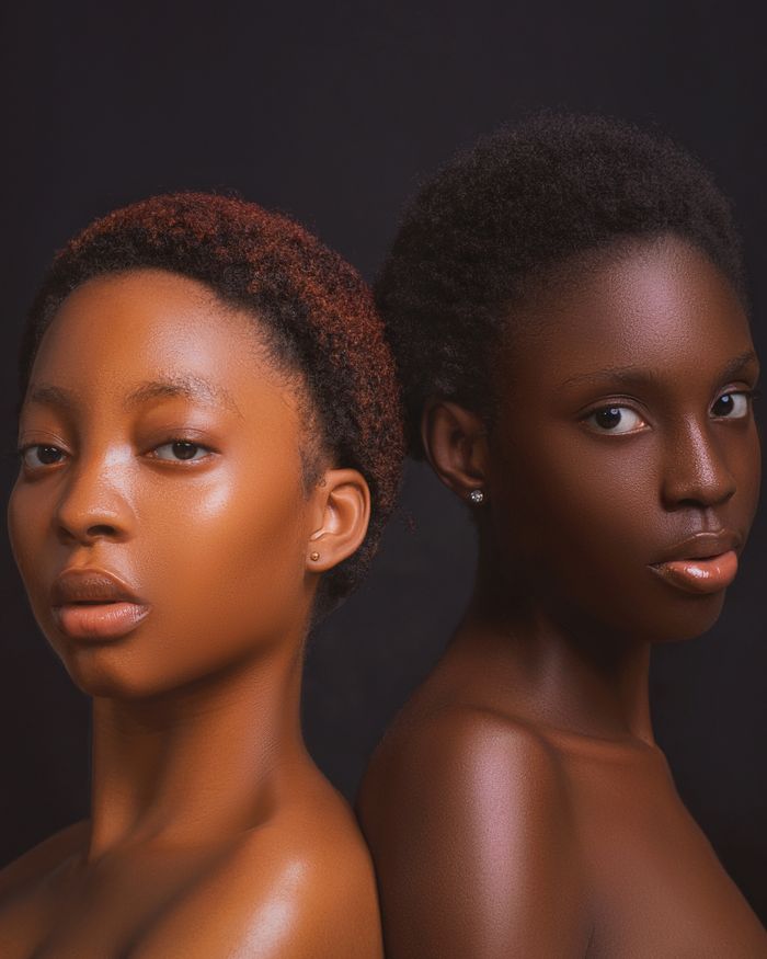 Studio portrait of two women with afro hair against a dark background showcasing beauty and sophistication.